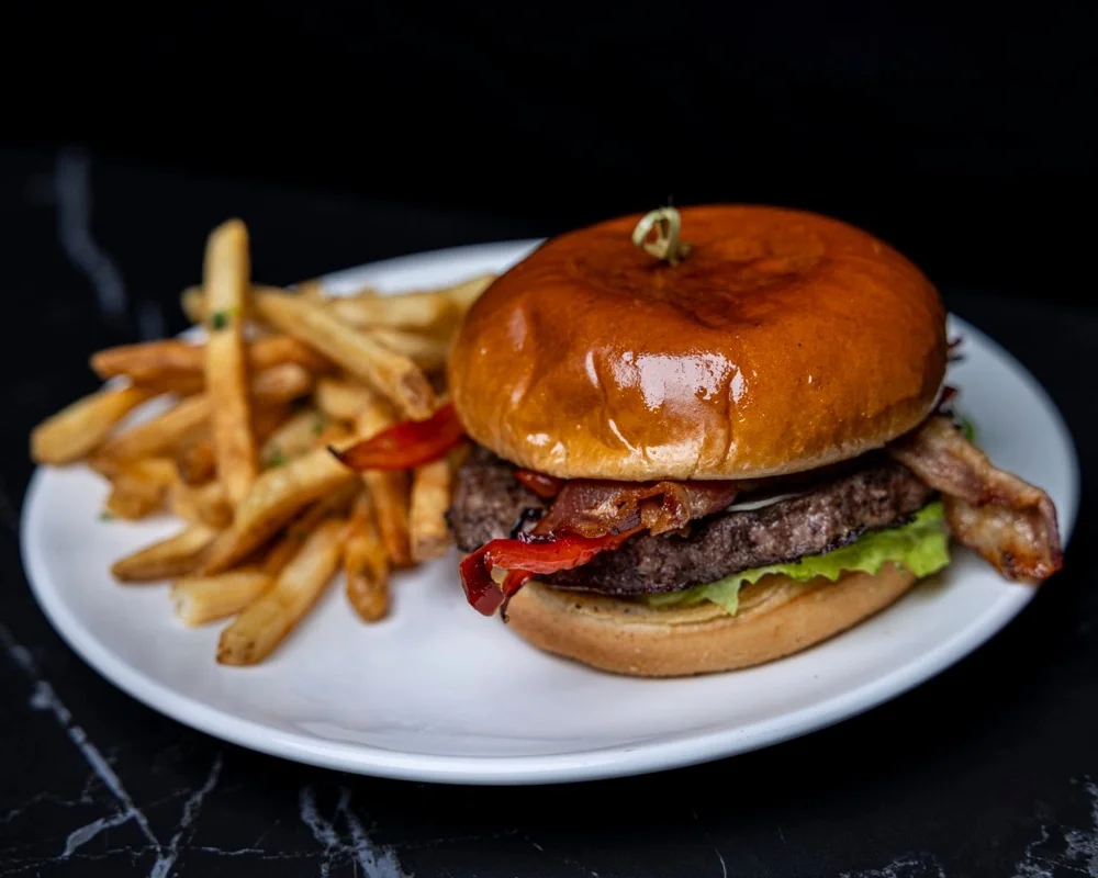 A premium burger on a brioche bun with fries at G.O.A.T's Arena
